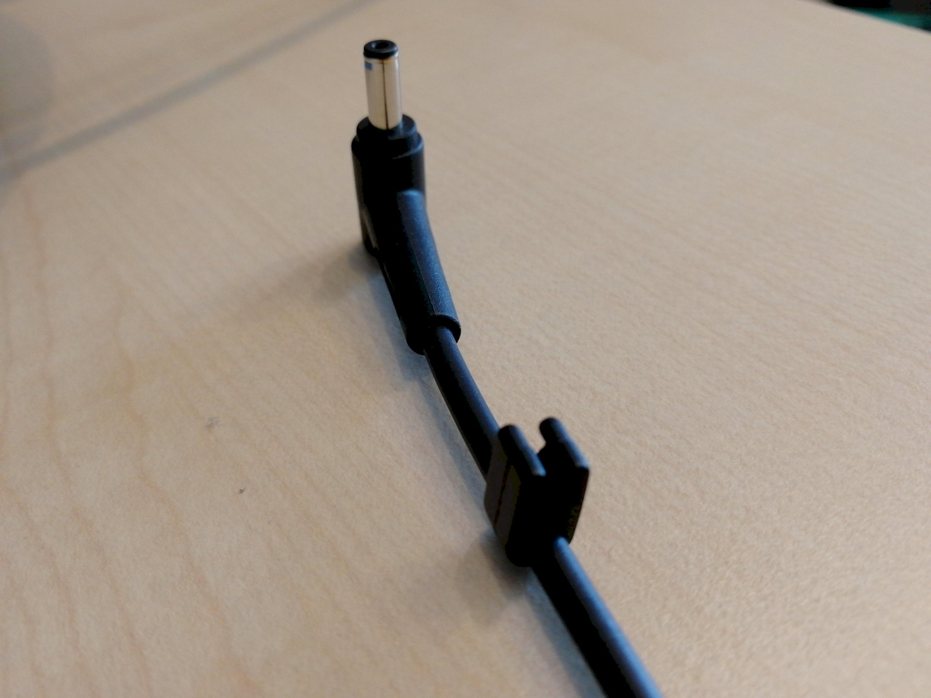 Why do some laptop charging cables have a round plastic eyelet